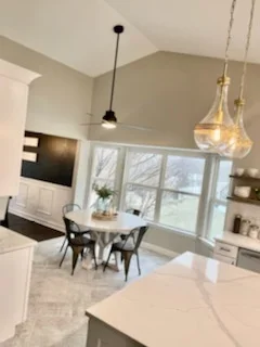 Modern kitchen with white cabinetry, quartz counters, pendant lights, and open dining area