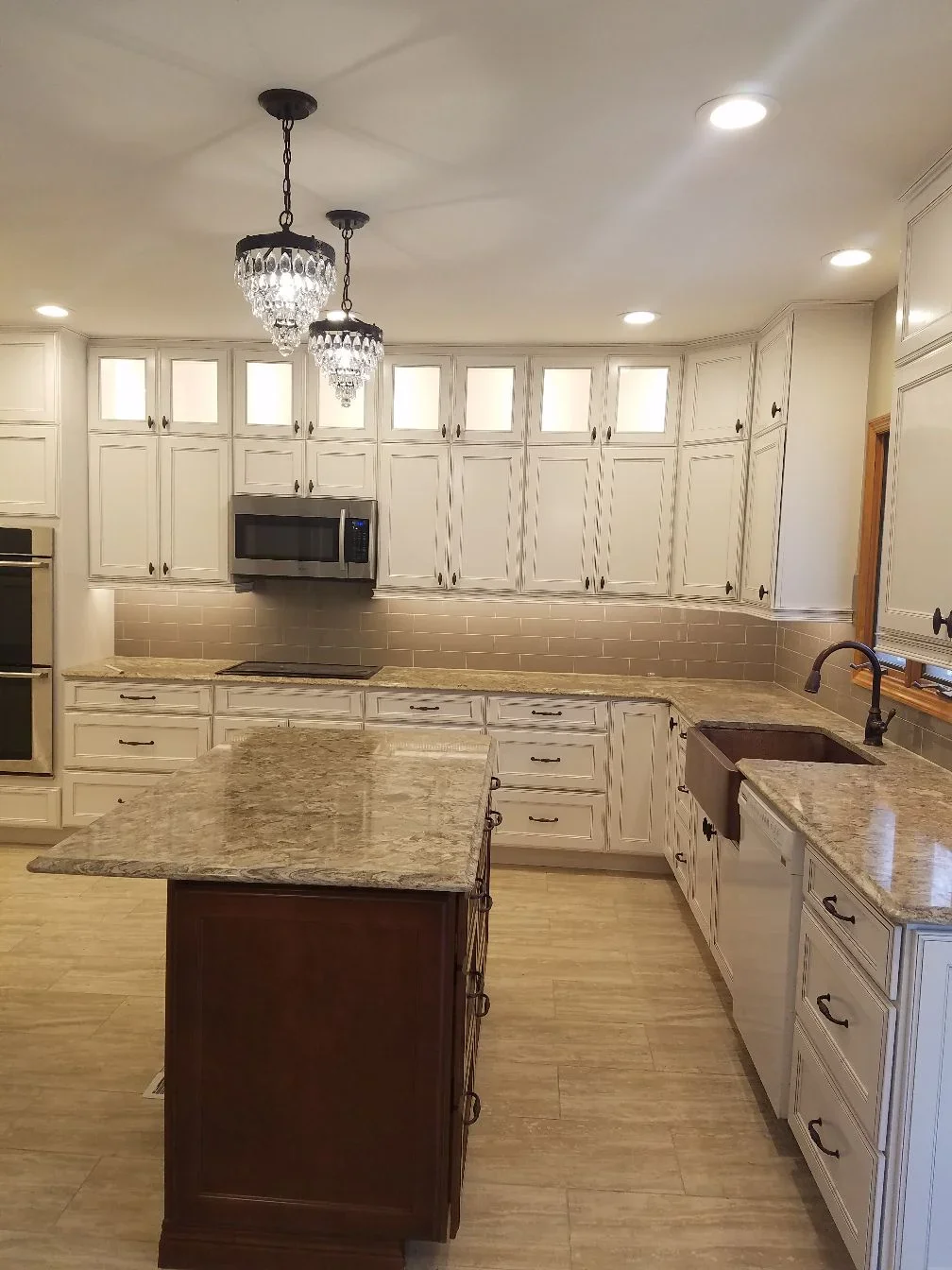 Cream cabinetry kitchen with granite counters, subway tile backsplash, and dark wood island