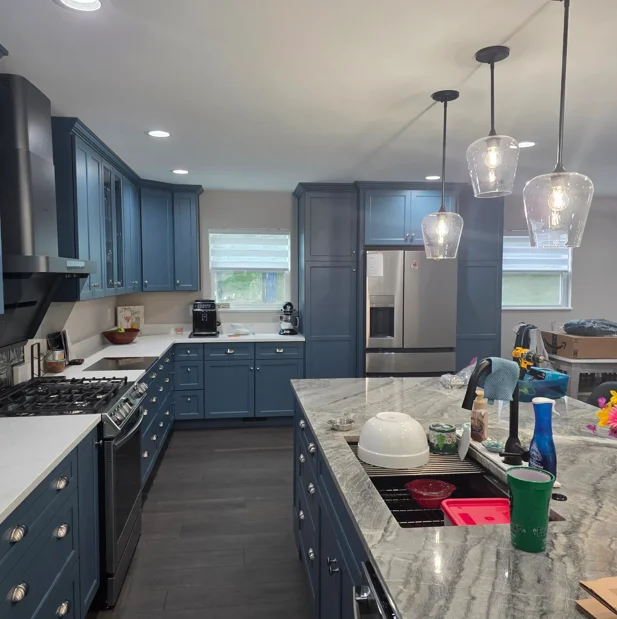 Navy cabinetry, quartz countertops, stainless steel appliances, pendant lights, dark flooring