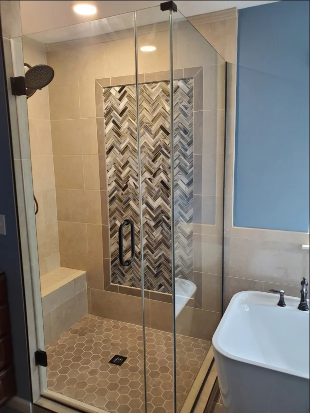 Frameless glass shower with herringbone tile accent wall and hexagonal floor tile