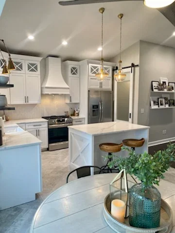 Modern kitchen with white cabinetry, quartz island, stainless steel appliances, and pendant lighting