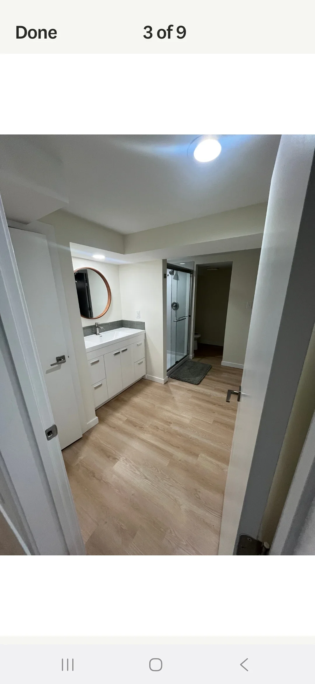 Renovated bathroom with white vanity, gray countertop, glass shower, and vinyl plank flooring