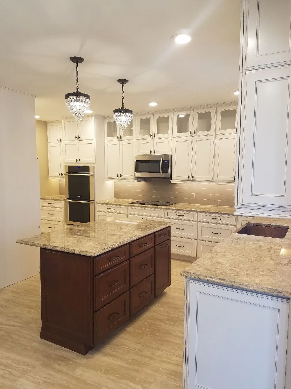 Cream cabinets, dark wood island, granite counters, subway tile backsplash, stainless steel appliances