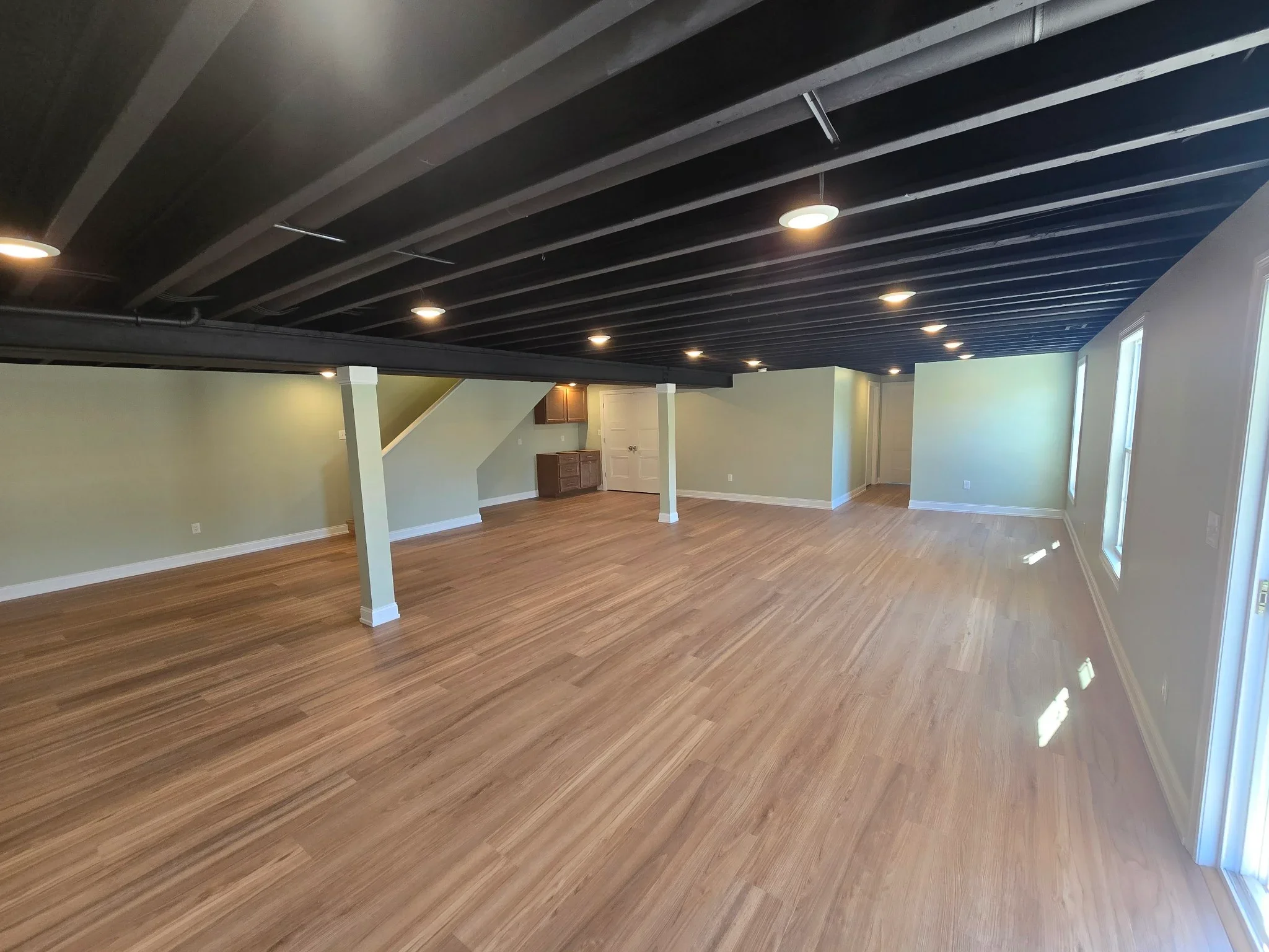 Finished basement with vinyl plank flooring, recessed lighting, and painted drywall walls