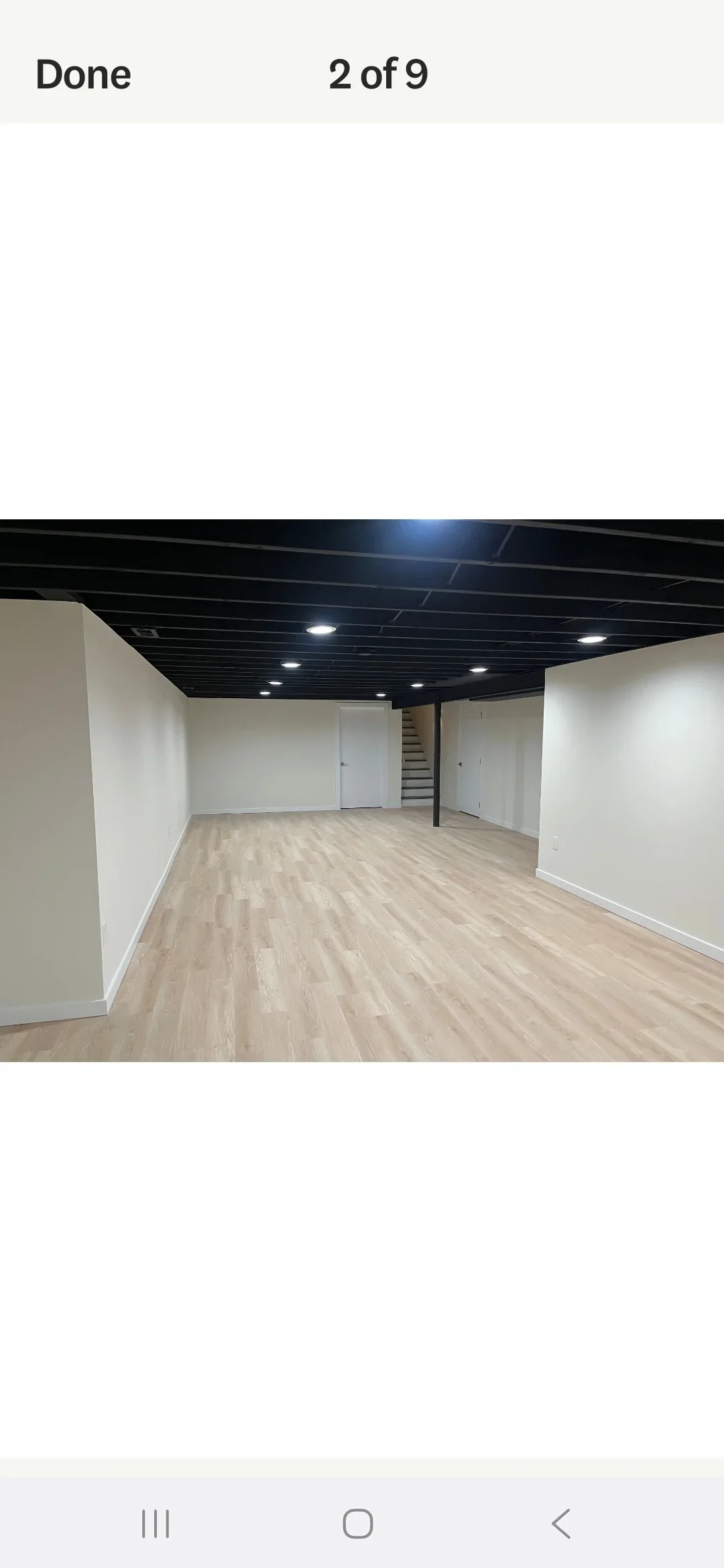 Finished basement with vinyl plank flooring, white drywall walls, and black drop ceiling with recessed lights