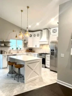 Modern kitchen with white cabinetry, quartz island, stainless steel appliances, and pendant lights